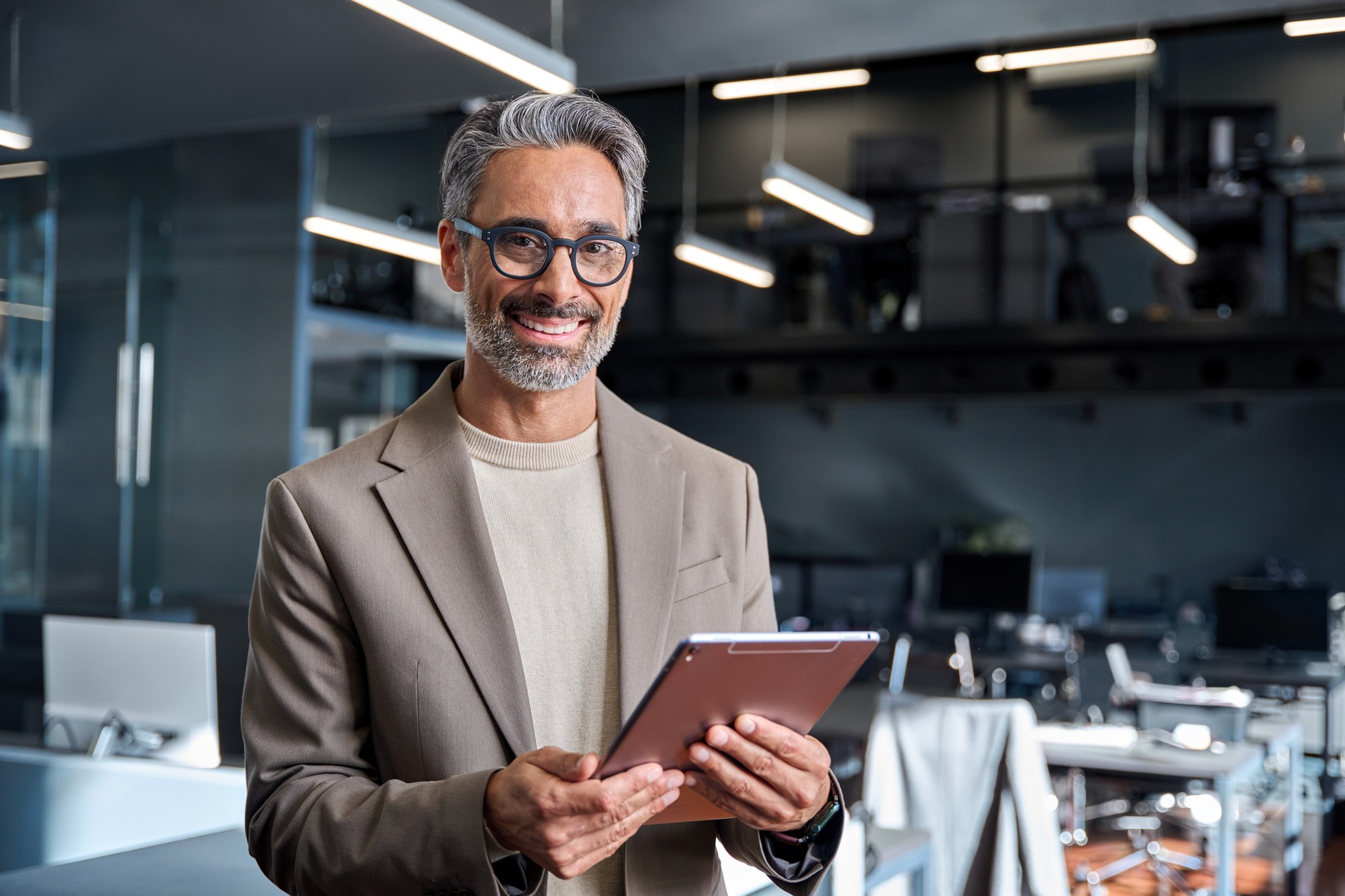 Executivo sorrindo com um tablet em um escritório moderno